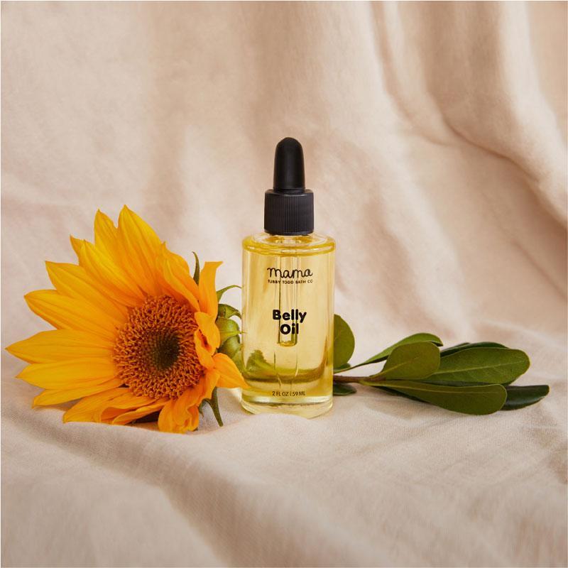 Belly Oil jar next to a sunflower stem